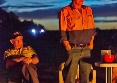 Either talking to the group, or he is just staring into the fire