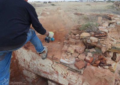 Ron blows loose dirt from the oven floor
